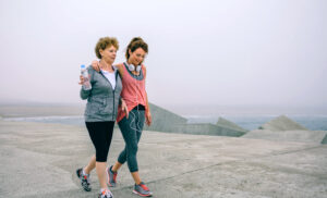 Two women walking by sea pier