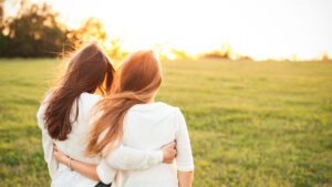 Young women in white sweaters are walking on the green field. Be